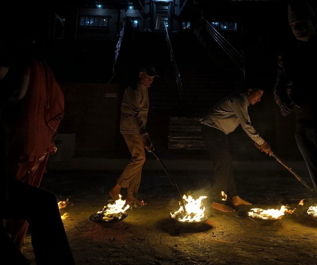 end of the ceremony, with people burning wood in metal vases in front of the temple.